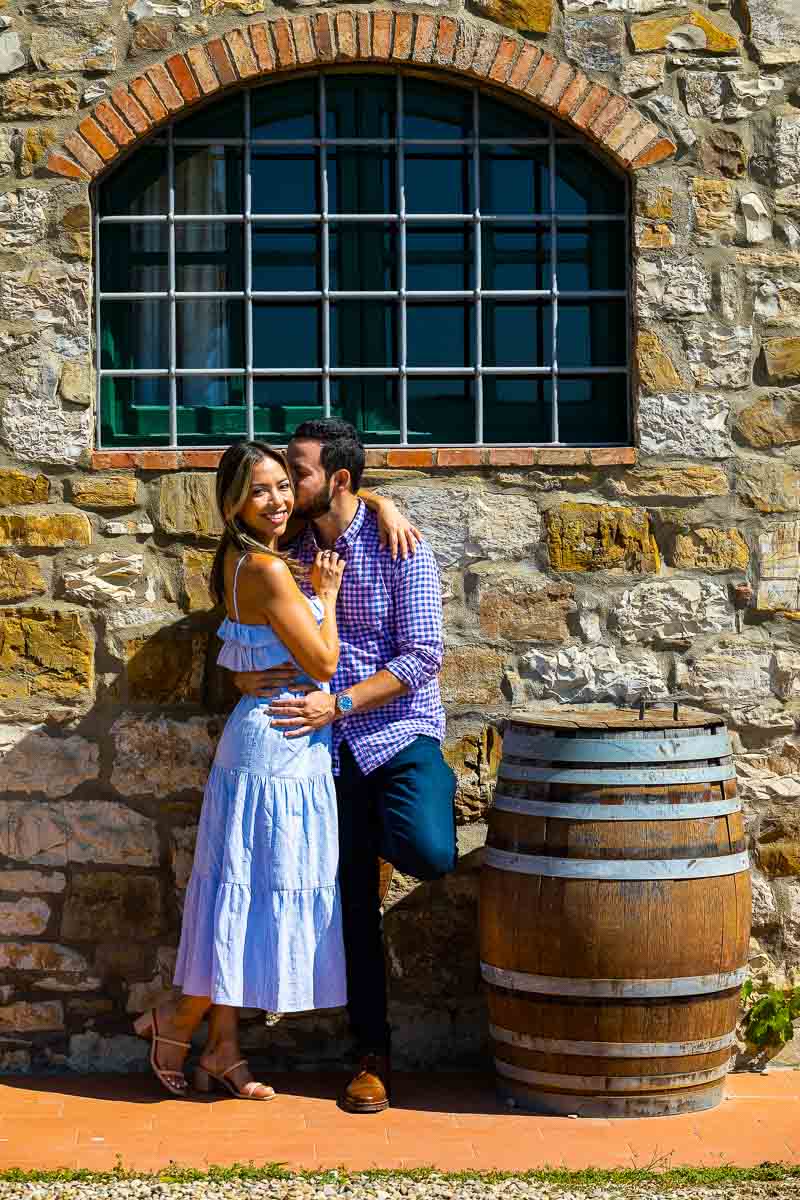 Couple posing next to a wooden barrel in a typical winery in Tuscany Italy