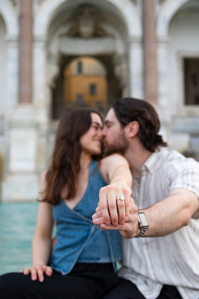 Couple kissing during their engagement photos showing the engagement ring in the forefront and having them out of focus in the background