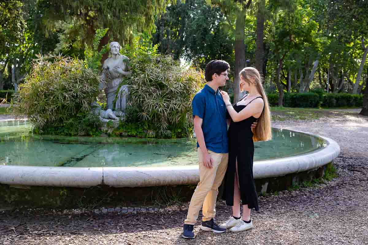 Together in Rome couple posing in front of a circular water fountain during and engagement photo shoot