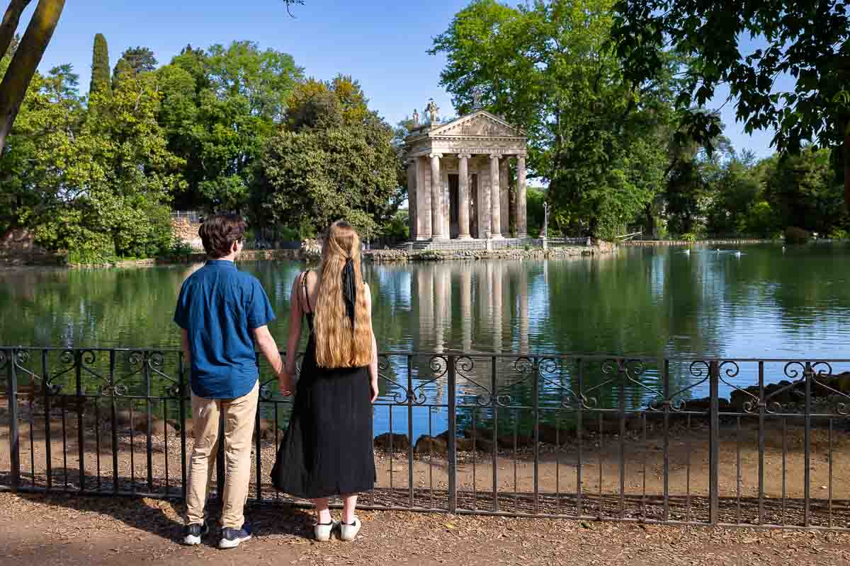 Admiring Temple of of Asclepius found on the edge of the Villa Borghese lake during an engagement photography session after a Marriage Proposal in Rome