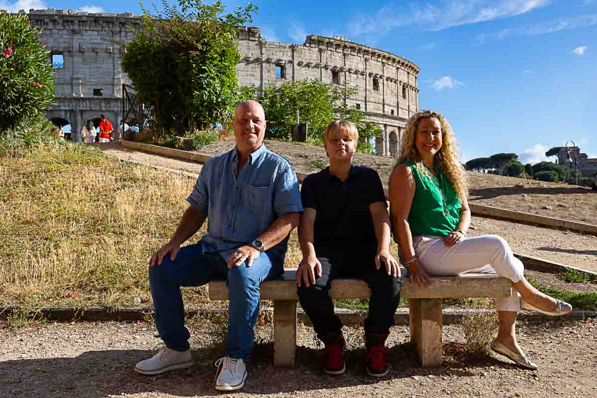 Sitting down family portrait on a marble bench just before the Roman Colosseum 