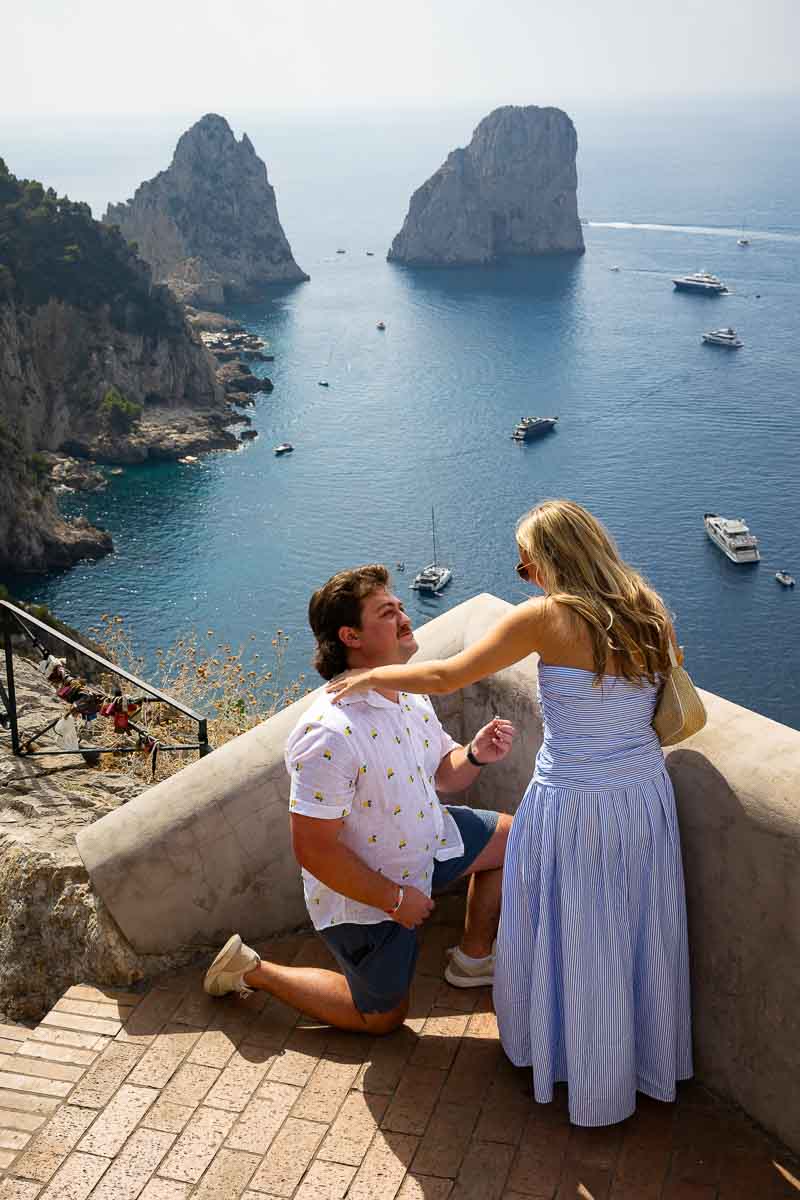 Kneeling down for a marriage proposal in Capri overlooking the Faraglioni rocks in the far distance 