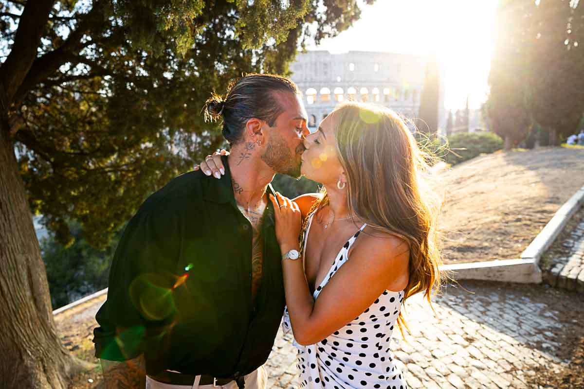 Couple kissing after proposal in Rome with the Colosseum in background at sunset 