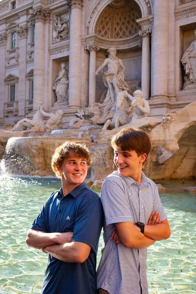 Back to back portrait guys looking at each other with the beautiful trevi fountain in the background