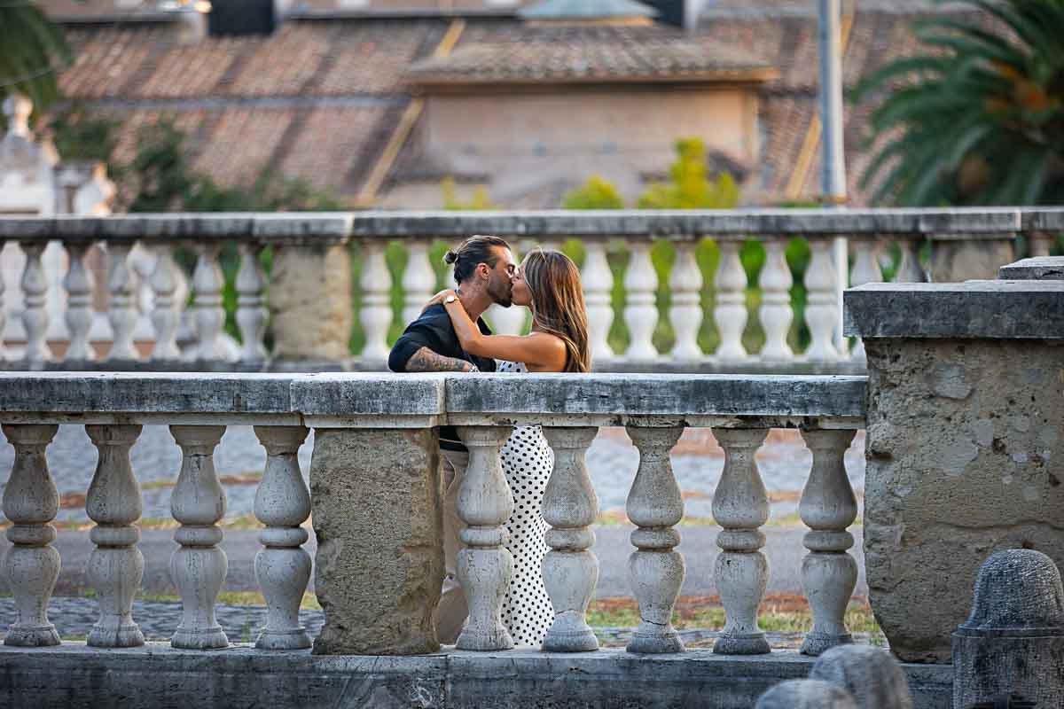 Photographed kissing between old ancient marble railing 