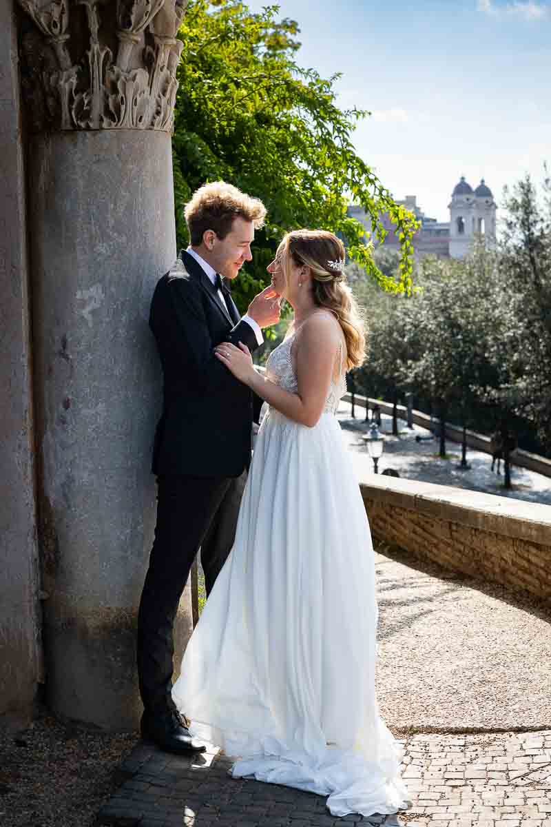 Bride and groom posing together by a roman pillar