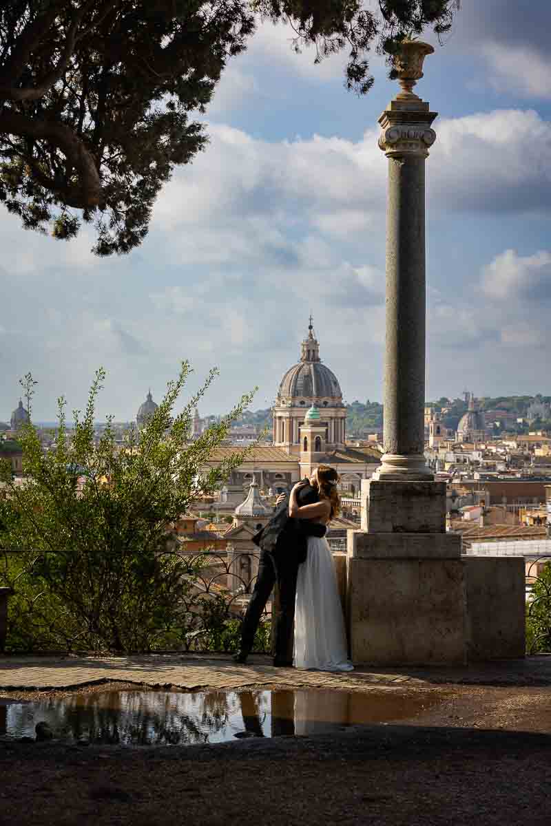 Scenic or more artistic photo take of the groom and the bride as they kiss before the sweeping view of the Roman skyline