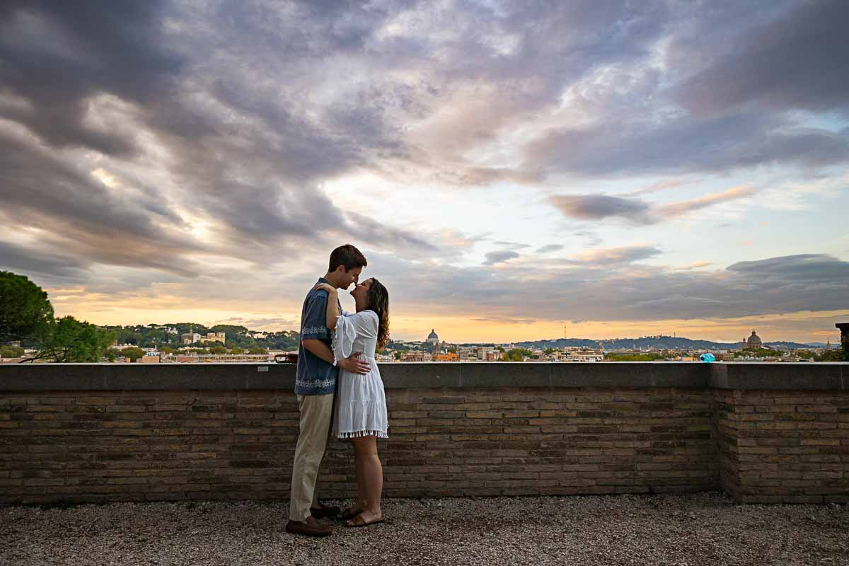 Romantic picture of a couple standing close together taking pictures before the sweeping view from the Giardino degli Aranci terrace