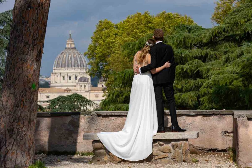 Wedding photoshoot in Rome with the bride and groom admiring the view of the Saint Peter's cathedral dome in the far distance