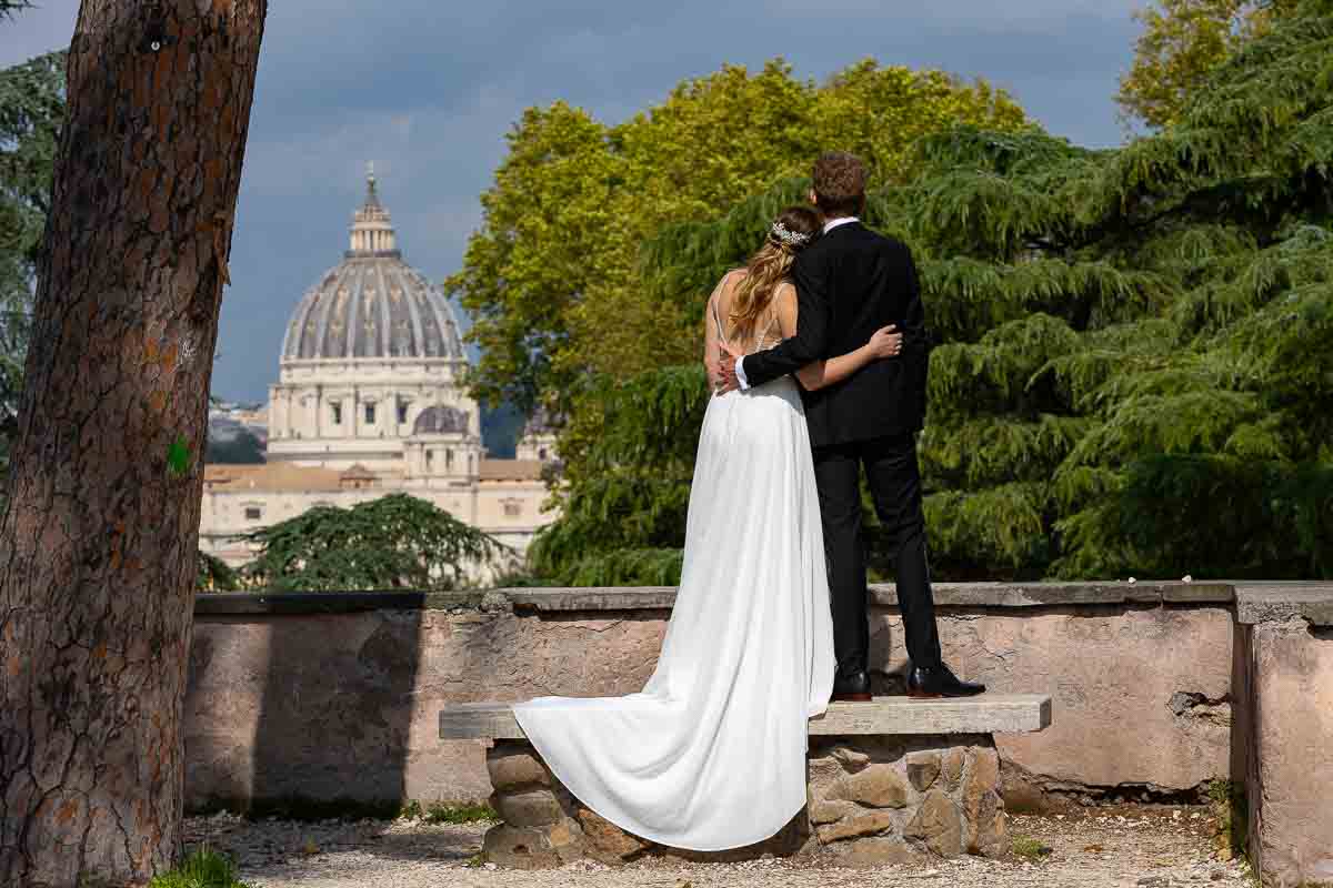 Wedding photoshoot with the bride and groom admiring the view of the Saint Peter's cathedral dome in the far distance. Rome Wedding Photography and Videography service 