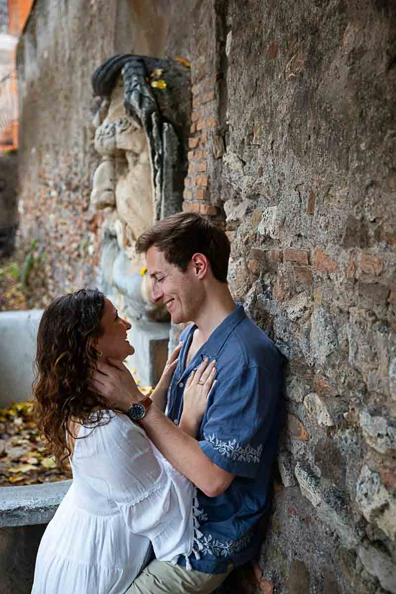 Portrait picture of a couple leaning against the wall by the fountain 