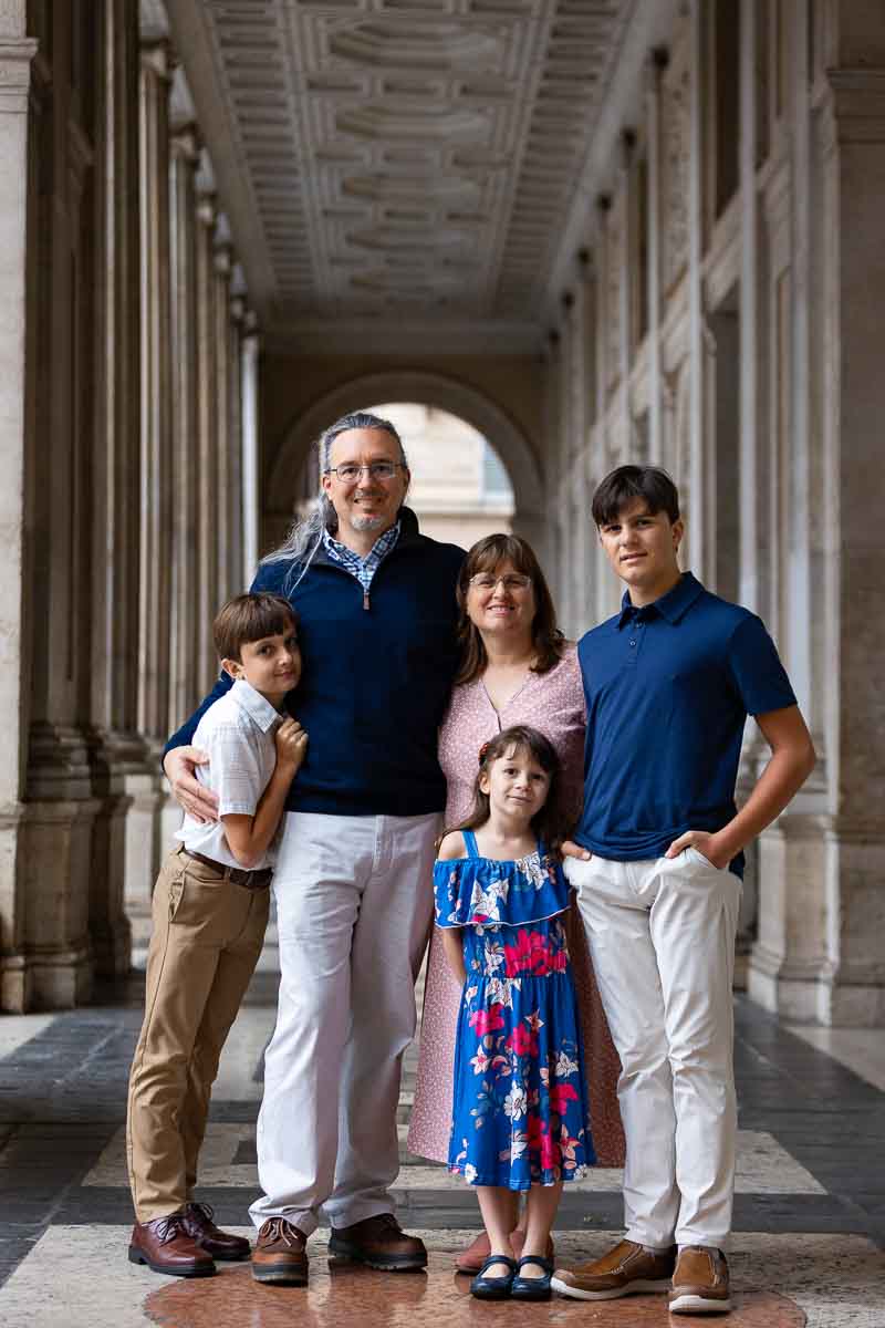 Vertical portrait of a family posing underneath a colonnade in Rome Italy