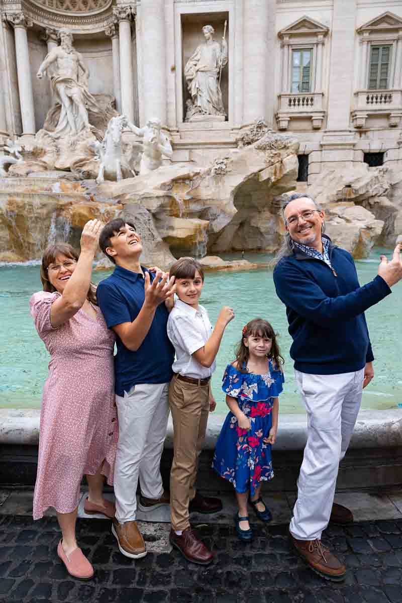 Family throwing the coin into the Trevi fountain during a photography session in Rome