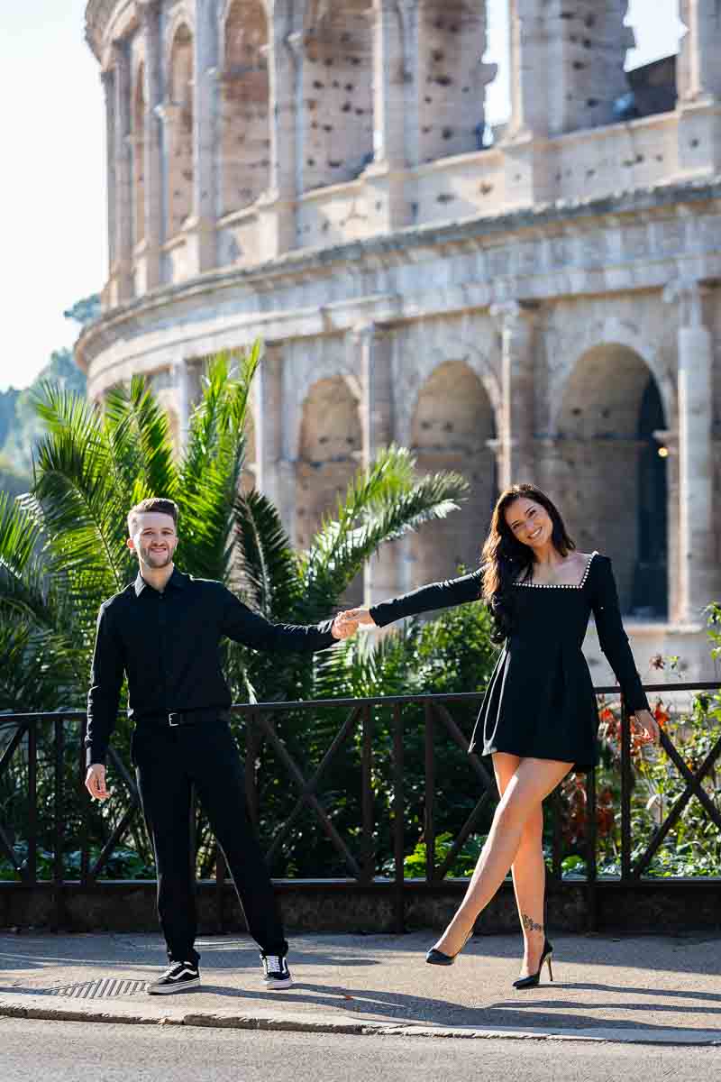 Couple holding hands while taking photos in Rome by the Colosseum for their engagement pictures 