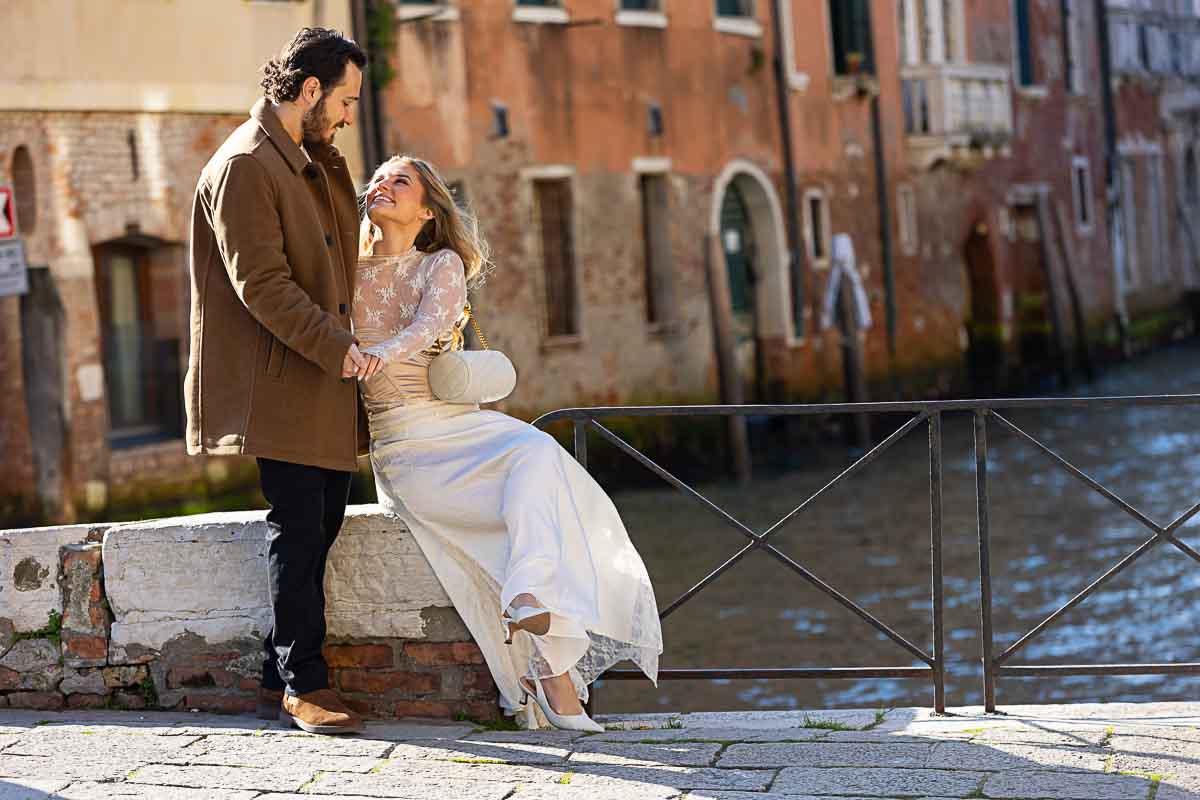 Posed couple sitting down by a venetian water canal 