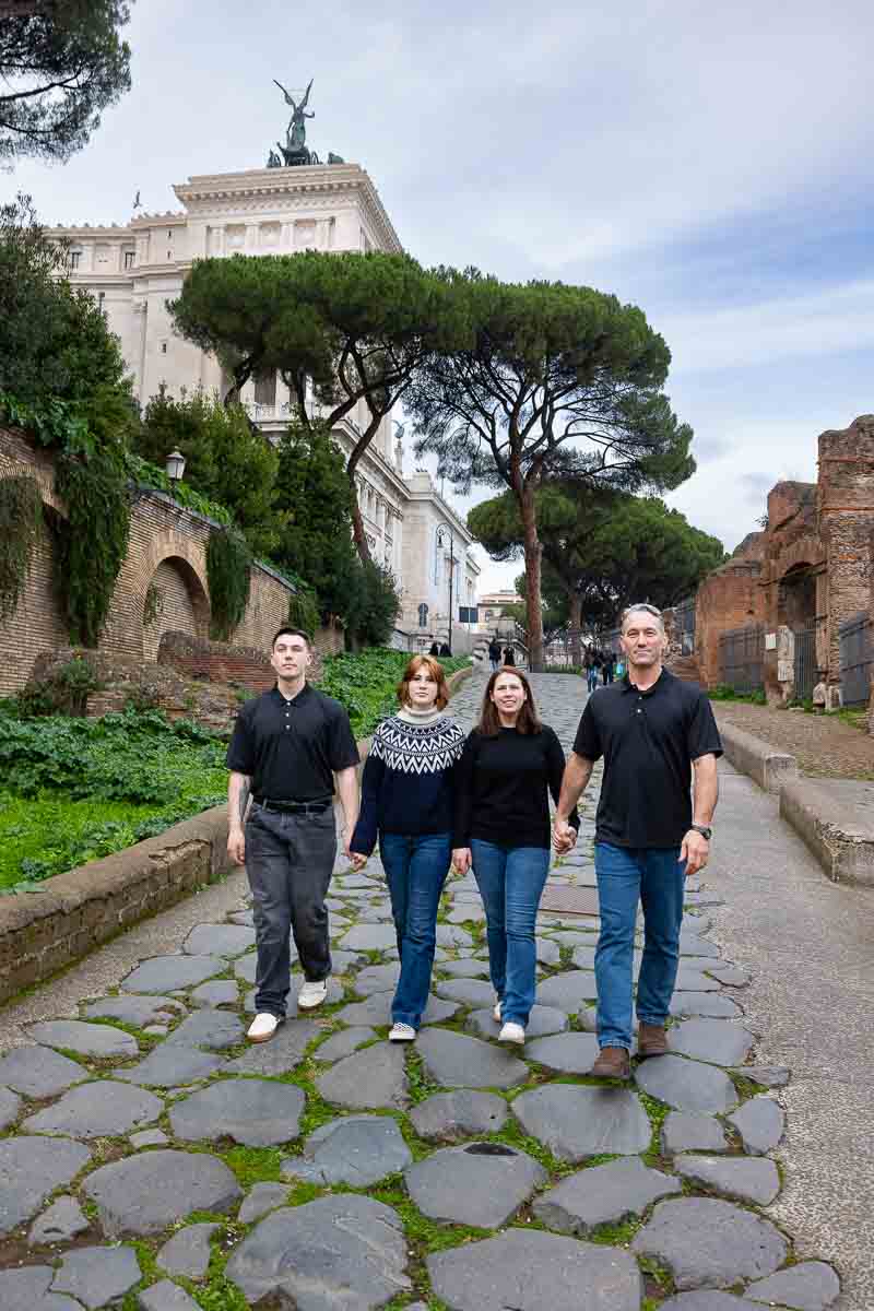 Walking together in Rome during a family photoshoot stepping on ancient roman road 