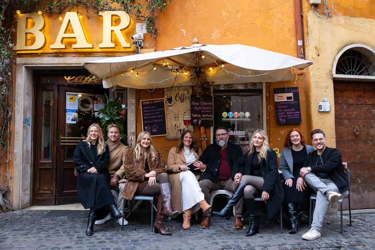 Sitting down portrait of everyone taking a picture by a bar in trastevere