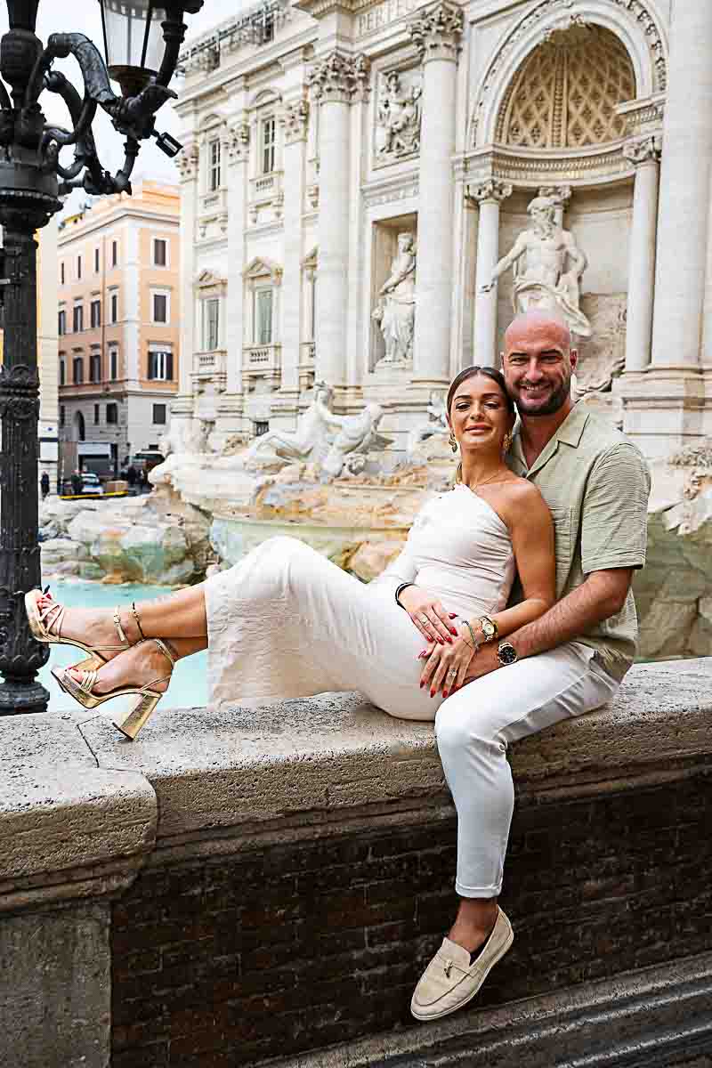 Portrait sitting down on a marble wall just before the facade of the Fontana di Trevi in Italy 