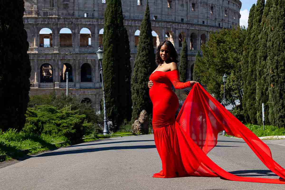 Solo maternity photos in red in front of the Colosseum in Rome Italy. Picture taken ina park overlooking the monument from a side street 